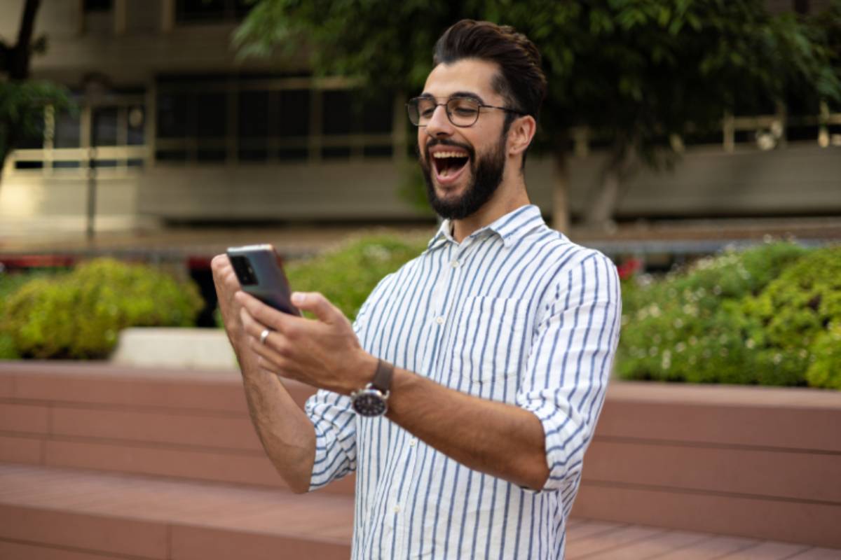 uomo che esulta con il cellulare in mano